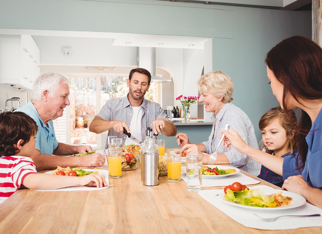 Personal Insurance - Family With Their Children and Grandparents Sit Together at a Dinner Table to Enjoy a Meal at Home