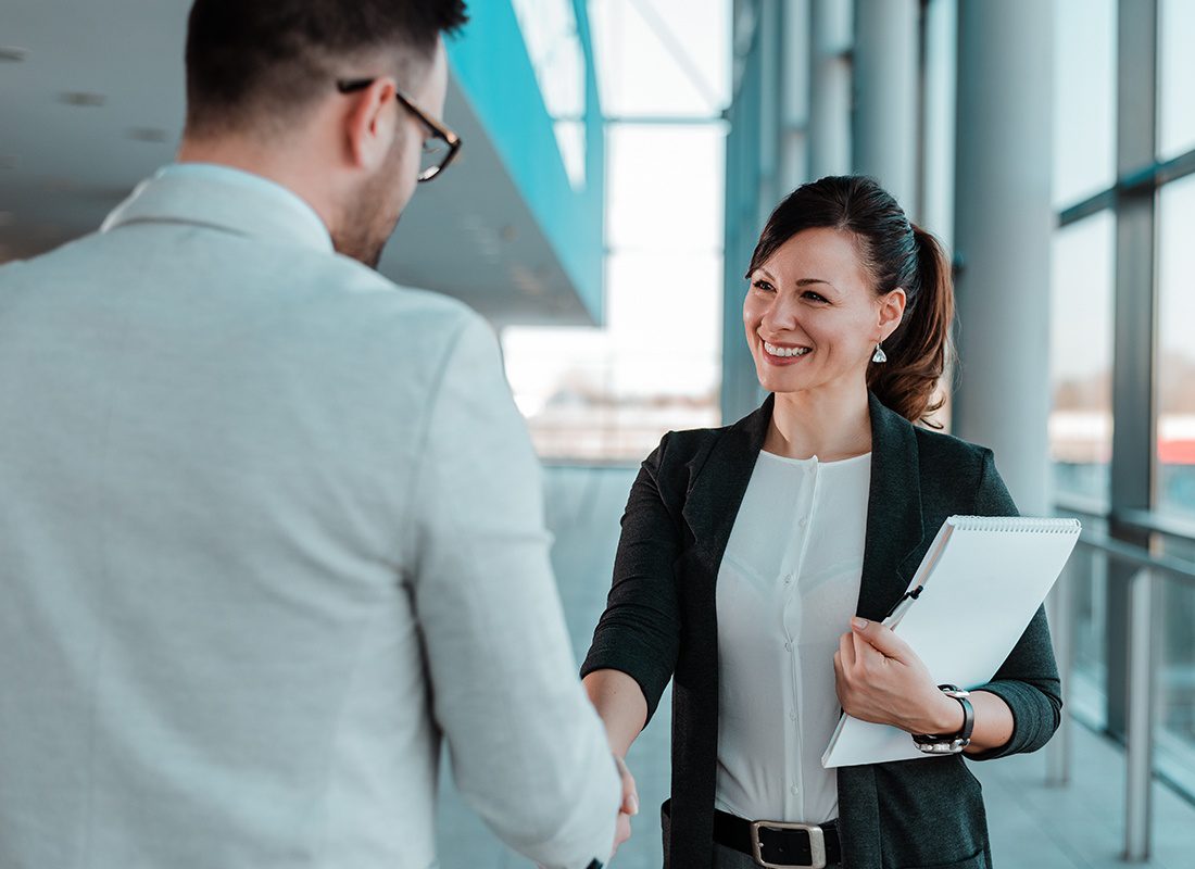 Contact - Friendly Business Woman Shakes Hands With a Colleague at an Office